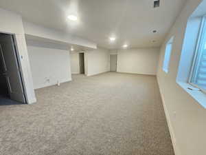 Below grade area featuring recessed lighting and light carpet