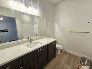 Full bathroom featuring a shower, vanity, and dark wood-style floors