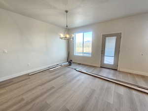 Unfurnished dining area featuring a chandelier and light wood-type flooring