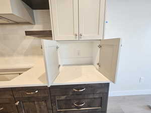 Kitchen with decorative backsplash, open shelves, light stone countertops, and dark wood finish cabinetry