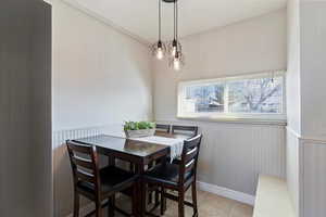 Dining area featuring wainscoting and light tile patterned flooring