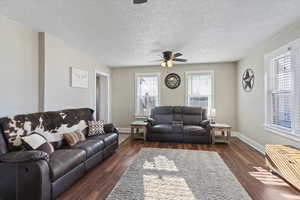 Living area featuring dark wood-style floors, a textured ceiling, and a ceiling fan