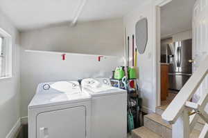 Laundry area with independent washer and dryer and vaulted ceiling