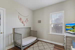Bedroom featuring a crib and dark wood-type flooring