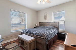Bedroom with dark wood-style flooring, ceiling fan, and a textured wall