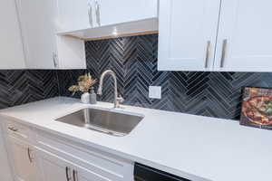 Kitchen with white cabinets, light stone counters, and tasteful backsplash