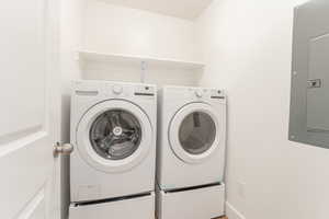 Laundry room with electric panel and washer and dryer