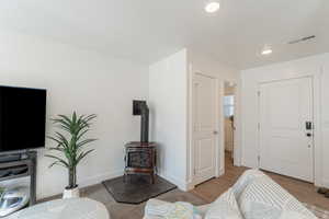 Living area with a wood stove, wood finished floors, and recessed lighting