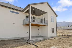 Rear view of property with a patio area, a mountain view, stucco siding, and a balcony