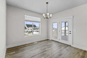 Unfurnished dining area with plenty of natural light, hanging lights, and light wood-style flooring
