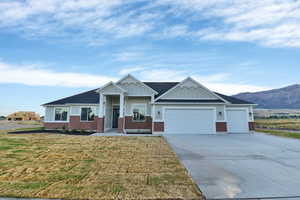 Craftsman-style house featuring board and batten siding, a front lawn, an attached garage, driveway, and brick siding