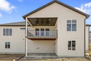 Back of house with a balcony, a patio area, and stucco siding