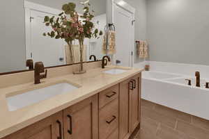 Bathroom featuring double vanity, a bath, and dark tile patterned flooring