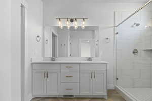 Bathroom featuring a shower stall and double vanity