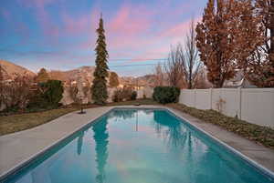 View of swimming pool featuring a fenced backyard, a mountain view, and patio surround