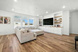 Living room featuring light wood finished floors, recessed lighting, and built in features