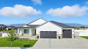 Modern inspired farmhouse featuring a mountain view, covered porch, and stone siding