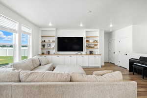 Living room with light wood-type flooring, built in features, and recessed lighting