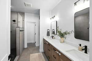Primary Full bathroom featuring a walk in shower, double vanity, and light tile patterned floors