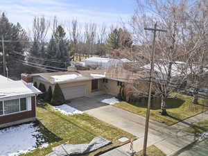 View of front of property with brick siding, a chimney, concrete driveway, an attached garage, and a front lawn