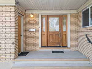 View of exterior entry with brick siding and covered porch
