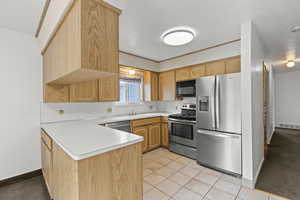 Kitchen with light countertops, stainless steel appliances, a peninsula, and light tile patterned floors