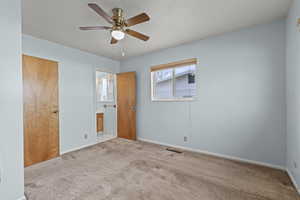 Unfurnished bedroom with carpet flooring, connected bathroom, and a ceiling fan