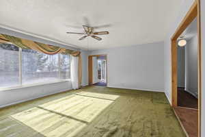 Unfurnished bedroom featuring carpet flooring, a ceiling fan, and a textured ceiling