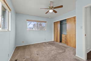 Unfurnished bedroom featuring carpet flooring, a closet, and a ceiling fan