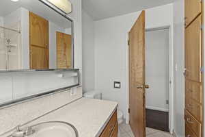 Bathroom featuring vanity, light tile patterned floors, and a shower