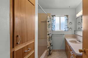 Full bath featuring shower / bath combo with shower curtain, vanity, and light tile patterned floors