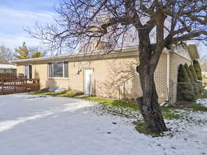 Snow covered property with brick siding and a wooden deck