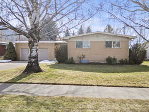 Ranch-style house featuring brick siding, a front lawn, driveway, and an attached garage