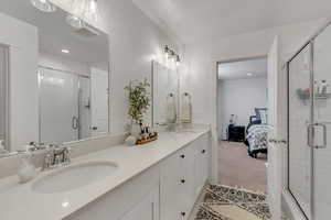 Ensuite bathroom featuring a shower stall, light carpet, double vanity, and recessed lighting