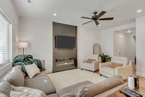 Living area with recessed lighting, a large fireplace, a ceiling fan, and wood finished floors