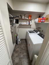 Laundry room with stone finish floors, independent washer and dryer, and heating unit