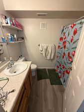 Full bathroom featuring vanity, a shower with shower curtain, and dark wood-type flooring