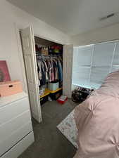 Bedroom with dark carpet and a closet