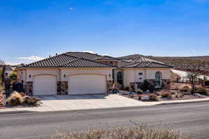 Mediterranean / spanish-style home with stone siding, stucco siding, driveway, and an attached garage