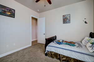 Carpeted bedroom featuring baseboards and ceiling fan