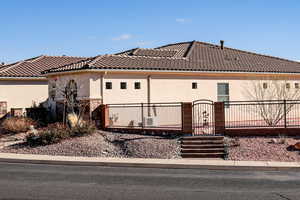 Rear view of property with a gate, a fenced front yard, stucco siding, and a tile roof
