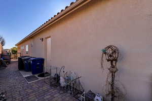 View of side of home featuring a patio area, stucco siding, and a gate