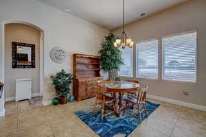 Dining area featuring arched walkways, light tile patterned floors, and a chandelier