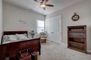 Bedroom featuring light colored carpet, a ceiling fan, and a closet