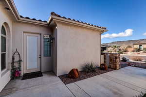Property entrance with stucco siding, a mountain view, and a tiled roof