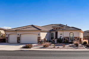 Mediterranean / spanish-style home featuring stone siding, stucco siding, concrete driveway, and a garage