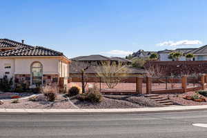 View of front of house with stucco siding, a gate, a tiled roof, and stone siding