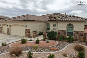 Mediterranean / spanish-style home featuring stucco siding, a garage, stone siding, concrete driveway, and a tile roof