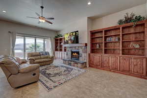 Living area with a ceiling fan, a fireplace, a textured ceiling, recessed lighting, and light tile patterned floors