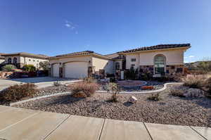 Mediterranean / spanish-style home with stone siding, concrete driveway, and stucco siding